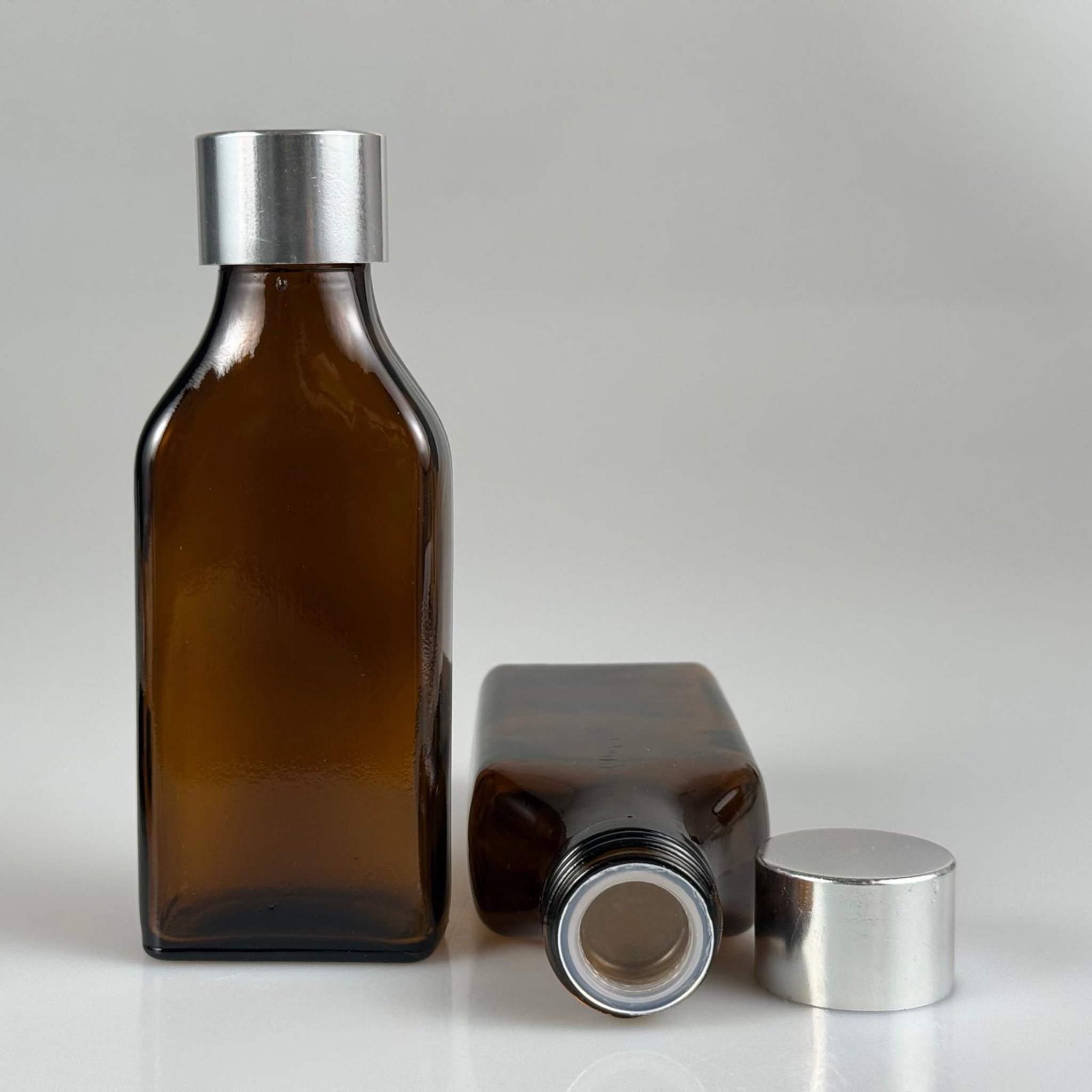 100 CC AMBER YASSI CAM ŞİŞE + ALÜMİNYUM KAPLAMALI GÜMÜŞ KAPAKLKI + KÖR TIPALI TAKIM - 100 ML KAYVERENGİ CAM ŞİŞE